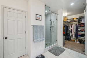 Full bathroom featuring a shower stall, a spacious closet, and recessed lighting
