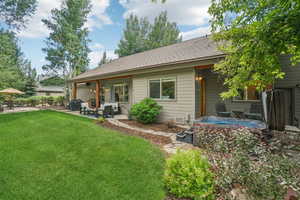 Back of property featuring a patio area, a lawn, and roof with shingles
