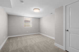Carpeted spare room featuring a smoke detector and baseboards
