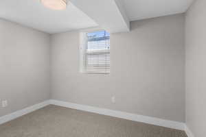 Carpeted spare room featuring baseboards