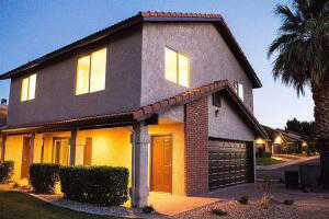 View of front of home with stucco siding and covered private entrance at sunset