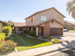 View of front of house with a front yard, concrete driveway, and stucco siding