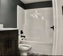 Full bathroom featuring  shower combination, vanity, and wood finished floors