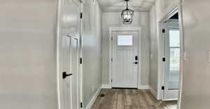 Foyer with light wood-style flooring, a chandelier, and plenty of natural light