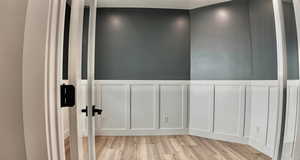 Spare room with a decorative wall, light wood-style floors, and a wainscoted wall