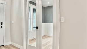 Corridor with light wood-type flooring and baseboards