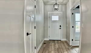 Foyer with light wood-style floors, plenty of natural light, and a chandelier