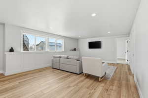 Living room with light wood-style flooring and recessed lighting