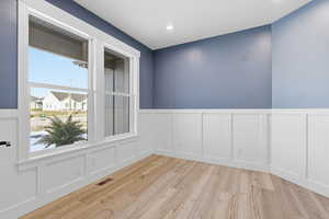 Unfurnished room featuring a decorative wall, a wainscoted wall, light wood-type flooring, and recessed lighting
