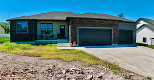 View of front of home with a garage, driveway, a shingled roof, and board and batten siding