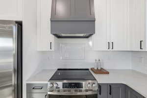 Kitchen featuring stainless steel appliances, light stone countertops, gray cabinets, and decorative backsplash