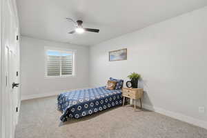 Carpeted bedroom featuring baseboards and a ceiling fan