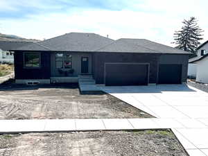 Ranch-style home with concrete driveway, a garage, and roof with shingles