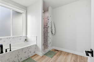 Bathroom featuring a garden tub, a tile shower, and light wood finished floors