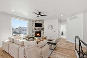 Living area featuring a stone fireplace, a ceiling fan, light wood-style flooring, and recessed lighting