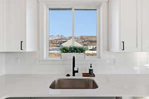 Kitchen featuring light stone counters, tasteful backsplash, white cabinetry, and a mountain view
