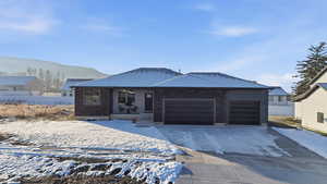 Ranch-style home with brick siding, an attached garage, concrete driveway, and a mountain view