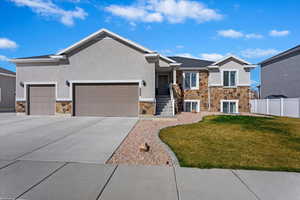 Ranch-style house with stone siding, an attached garage, driveway, and stucco siding