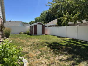 Fenced backyard featuring a shed