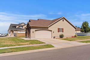 View of side of property with an attached garage, concrete driveway, and stucco siding