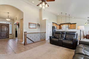 Living area featuring light tile patterned flooring, high vaulted ceiling, a ceiling fan, recessed lighting, and arched walkways