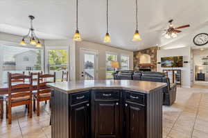 Kitchen featuring light tile patterned flooring, ceiling fan, plenty of natural light, a fireplace, and vaulted ceiling