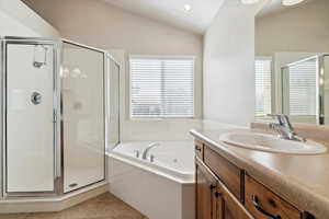 Primary bathroom featuring vaulted ceiling, vanity, a stall shower, a whirlpool tub, and recessed lighting