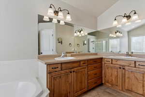 Primary full bathroom with double vanity, a garden, jetted tub, tile patterned floors, vaulted ceiling, and a stall shower