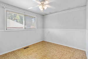 Empty room featuring a wainscoted wall and a ceiling fan
