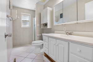 Full bathroom featuring tile walls, vanity, an enclosed shower, and tile patterned floors