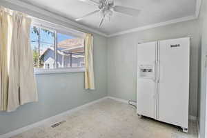 Kitchen featuring white fridge with ice dispenser, marble finish flooring, a ceiling fan, and ornamental molding