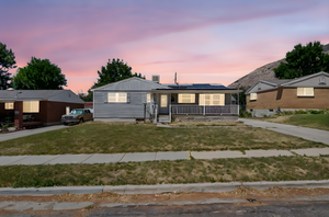 View of front of property featuring covered porch, roof mounted solar panels, a yard, and board and batten siding