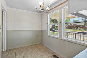 Unfurnished dining area with a chandelier and ornamental molding