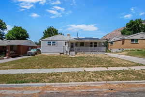 View of front of home featuring a porch, roof mounted solar panels, a front yard, and board and batten siding