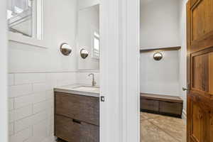 Bathroom featuring vanity, tile walls, and concrete floors