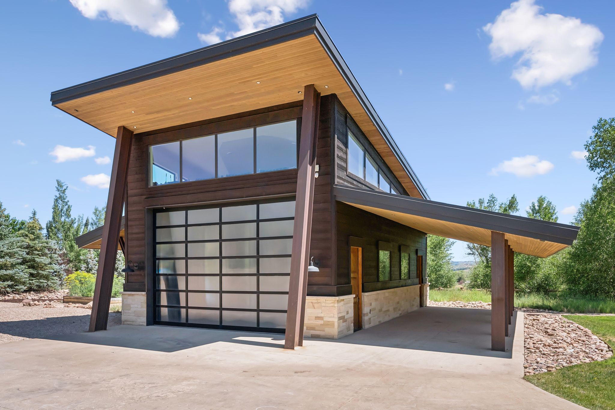 View of side of home featuring driveway, stone siding, and a garage
