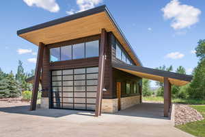 View of side of home featuring driveway, stone siding, and a garage