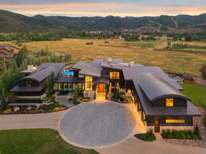 View of front of house with curved driveway, a chimney, a metal roof, and a mountain view