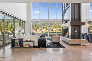 Living area featuring a high ceiling, a large fireplace, plenty of natural light, and finished concrete flooring