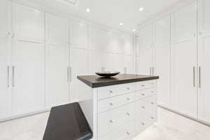 Walk in closet featuring light marble finish floors