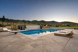 View of pool featuring a diving board, a mountain view, and a patio area