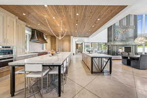 Kitchen with wooden ceiling, a spacious island, recessed lighting, premium range hood, and light stone counters