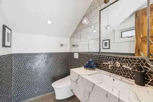 Bathroom featuring lofted ceiling, tile walls, and vanity