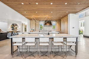 Kitchen with wooden ceiling, custom exhaust hood, a spacious island, recessed lighting, and a breakfast bar area
