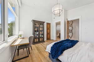 Bedroom featuring light wood-type flooring, a towering ceiling, and ensuite bathroom