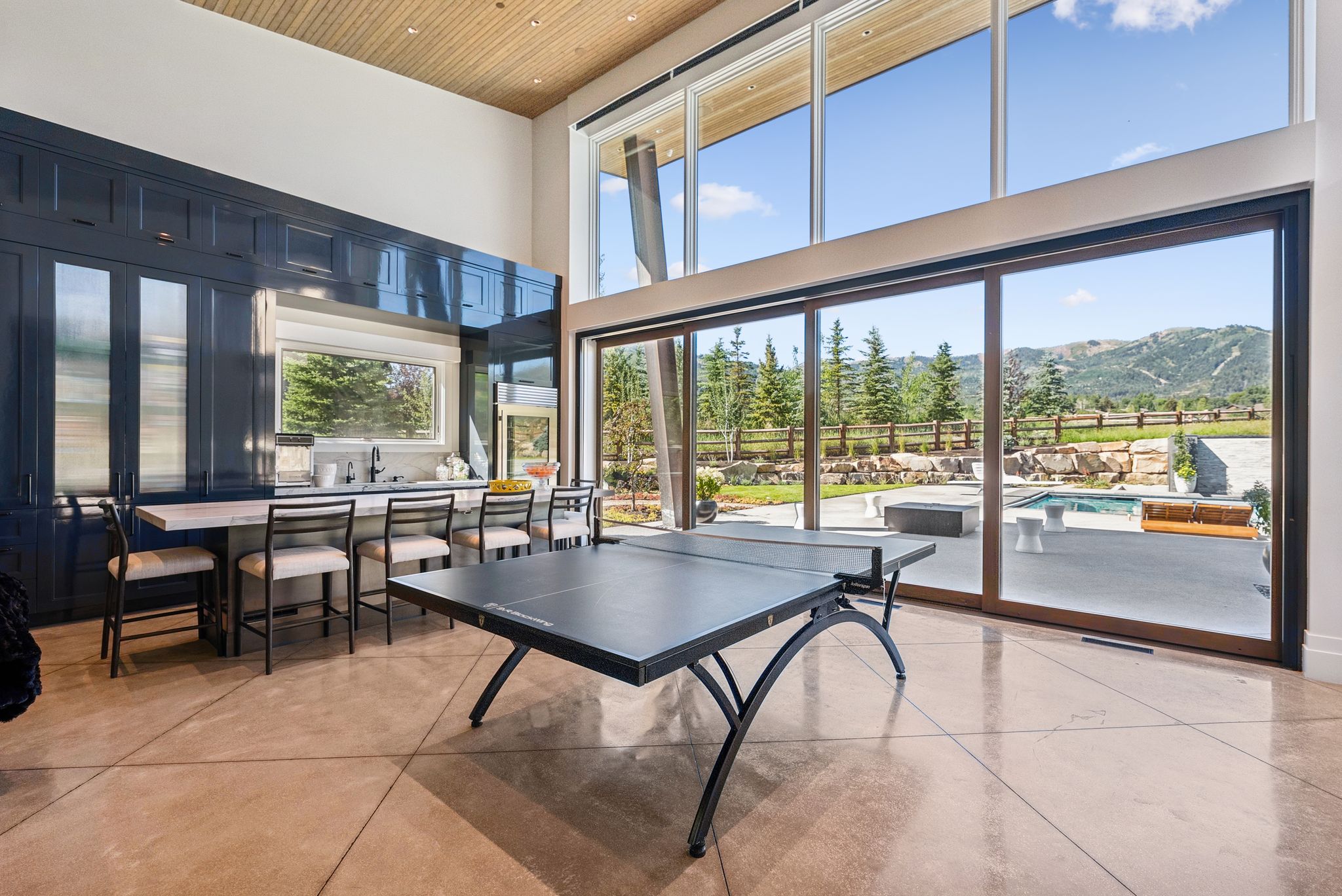 Rec room featuring a high ceiling, finished concrete flooring, and wooden ceiling