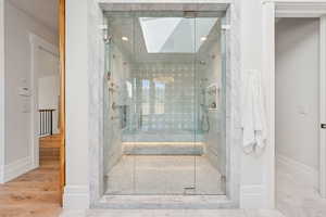 Bathroom featuring a shower stall, a skylight, and wood finished floors