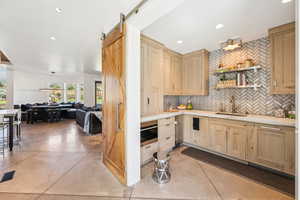 Kitchen with light brown cabinets, tasteful backsplash, light countertops, open floor plan, and recessed lighting