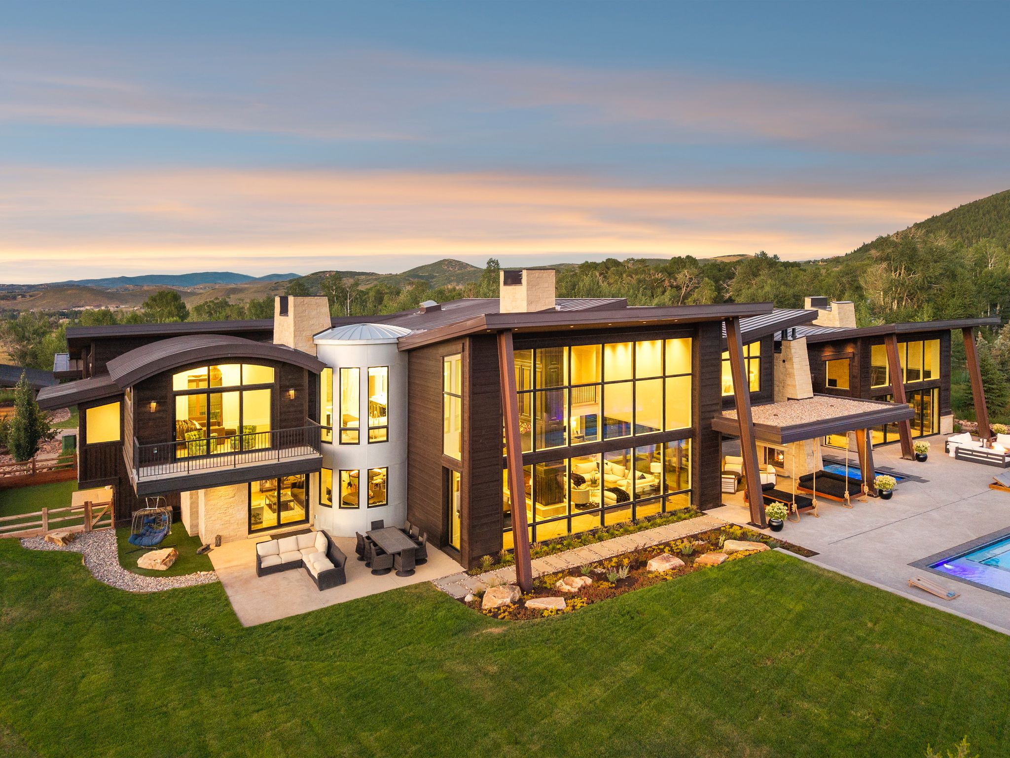 Back of property at dusk with an outdoor hangout area, a balcony, a chimney, a patio, and an outdoor pool