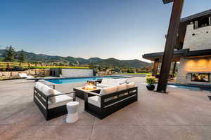 Swimming pool featuring a mountain view, an outdoor living space with a fireplace, and a patio area